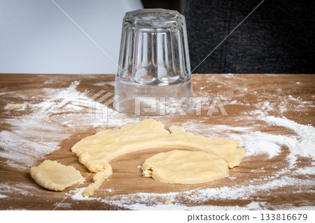 Cutting Dough Circles With an Upside-Down Glass on a Floured Wooden Surface Cutting Dough Circles With an Upside-Down Glass on a Floured Wooden Surface 133816679