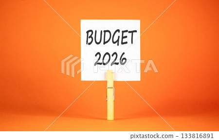 Budget 2026 symbol. Concept words Budget 2026 on beautiful white paper on wooden clothespin. Beautiful orange background. Business and budget 2026 concept. Copy space. Budget 2026 symbol. Concept words Budget 2026 on beautiful white paper on wooden clothespin. Beautiful orange background. Business and budget 2026 concept. Copy space. 133816891