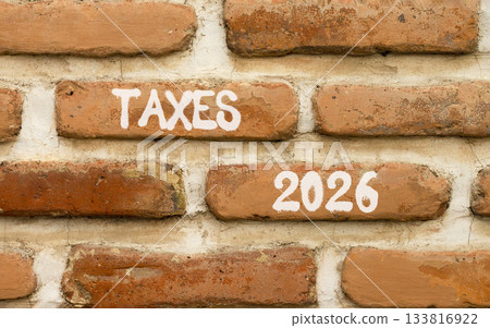 Taxes 2026 new year symbol. Concept words Taxes 2026 on beautiful brown brick wall. Beautiful brown brick wall background. Business and taxes 2026 new year concept. Copy space. 133816922