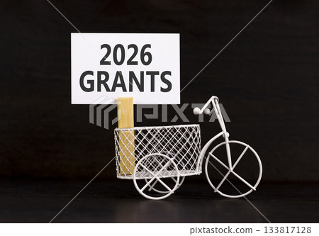 2026 Grants symbol. Concept words 2026 Grants on beautiful white paper on wooden clothespin. Beautiful black background. Beautiful miniature bicycle. Business and 2026 grants concept. Copy space. 2026 Grants symbol. Concept words 2026 Grants on beautiful white paper on wooden clothespin. Beautiful black background. Beautiful miniature bicycle. Business and 2026 grants concept. Copy space. 133817128