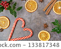 Christmas composition. Christmas candy canes with branches of holly, anis stars, cinnamon sticks, oranges. High quality photo 133817348