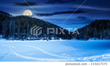 winter landscape with snow covered ground at night. mountains with frozen lake among spruce forest in full moon light. scenic view of winter wonderland. background for investment or abstract concepts winter landscape with snow covered ground at night. mountains with frozen lake among spruce forest in full moon light. scenic view of winter wonderland. background for investment or abstract concepts 133817375