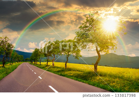 trees along the country road in to mountains at sunset. beautiful summer landscape with epic clouds in evening light. motion blur effect. leadership corporate wallpaper under the rainbow trees along the country road in to mountains at sunset. beautiful summer landscape with epic clouds in evening light. motion blur effect. leadership corporate wallpaper under the rainbow 133817398