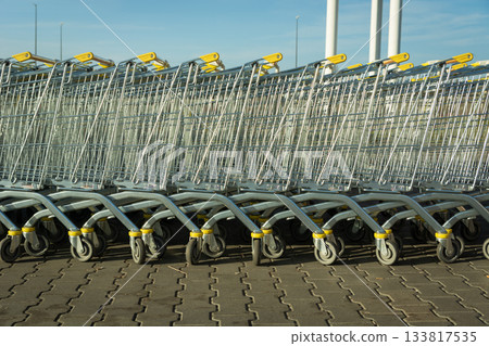Row of large nested shopping carts on an outdoor store parking lot 133817535