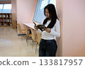 Asian Student Reading Book While Standing in Library Learning Space 133817957