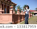 Asian Woman Photographing Traditional Temple Outdoors on Sunny Day 133817959