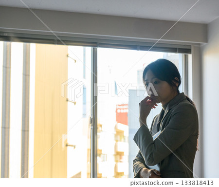 一位二十多歲的女商人倚窗沉思的肖像 133818413