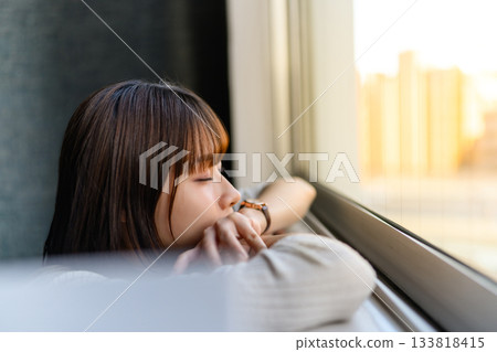 窗邊，一位年輕女子陷入沉思。 133818415