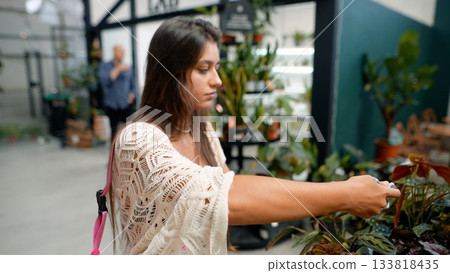 A Woman Engaging in an Enthusiastic Exploration of Various Plants Inside a Floral Shop 133818435