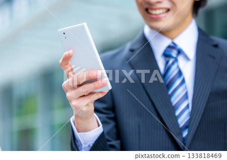 Hands of a young businessman operating a smartphone in the office Hands of a young businessman operating a smartphone in the office 133818469