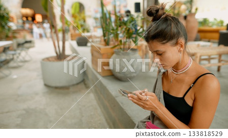 Woman Engrossed in Her Phone in a Trendy Caf 133818529