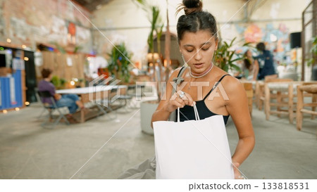 A young woman is seen opening her stylish bag in a trendy setting that reflects modernity 133818531