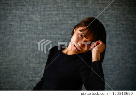 Upper body portrait of a young woman with a pensive expression against a dark background 133818690