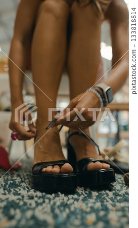 A woman tries on black heels in a stylish boutique, showcasing her love for modern fashion A woman tries on black heels in a stylish boutique, showcasing her love for modern fashion 133818814
