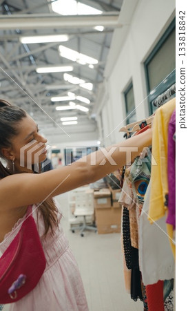 A Fashion Shopper Happily Exploring a Colorful Clothing Rack Inside a Modern Boutique A Fashion Shopper Happily Exploring a Colorful Clothing Rack Inside a Modern Boutique 133818842