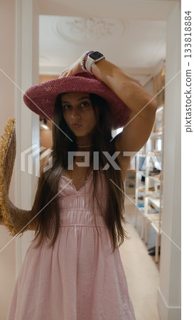 Chic and Stylish Summer Outfit Featuring a Vibrant Pink Hat in a Bright Boutique Setting Chic and Stylish Summer Outfit Featuring a Vibrant Pink Hat in a Bright Boutique Setting 133818884