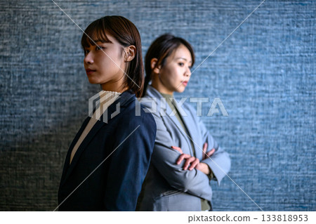 Two Japanese businesswomen standing back to back with a tense atmosphere 133818953