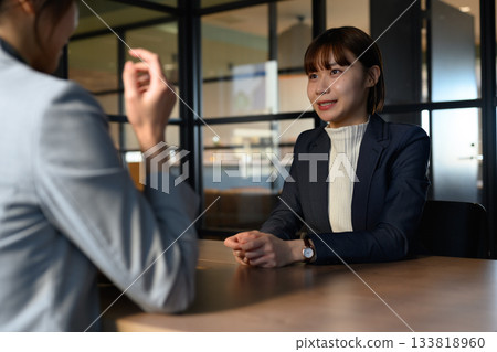 Smiling young female business person talking during an interview or business meeting in the office 133818960