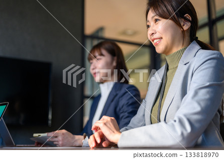 兩位日本女商務人士在會議上面微笑,神采奕奕。 兩位日本女商務人士在會議上面微笑,神采奕奕。 133818970