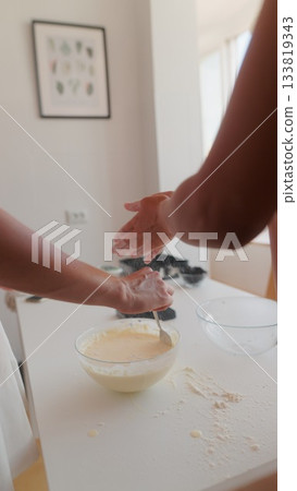 Hands are busily mixing a variety of ingredients in a bright and welcoming kitchen setting Hands are busily mixing a variety of ingredients in a bright and welcoming kitchen setting 133819343