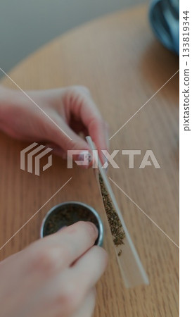 Rolling a Joint with Herbal Material in a Cozy and Inviting Setting for a Great Experience 133819344