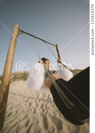 A Fashionable Swinging Model Posing Stylishly on the Beach Against a Beautiful Sunset Sky A Fashionable Swinging Model Posing Stylishly on the Beach Against a Beautiful Sunset Sky 133819379
