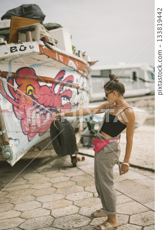 A Young Woman Happily Enjoying a Fun Pose in Front of a Beautifully Colorful GraffitiDecorated Boat 133819442