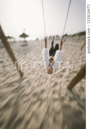 Swinging joyfully on the beautiful beach during the stunning sunset, feeling carefree and joyful Swinging joyfully on the beautiful beach during the stunning sunset, feeling carefree and joyful 133819471