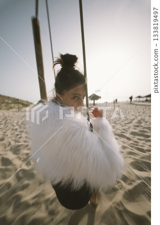 An Elegant Swinging Model Posing on the Beautiful Beach with a Stunning Sunset Glow 133819497