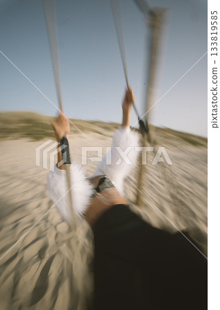 Experiencing the Joyful Swinging on a Beautiful Beach During a Serene Sunset Hour Experiencing the Joyful Swinging on a Beautiful Beach During a Serene Sunset Hour 133819585