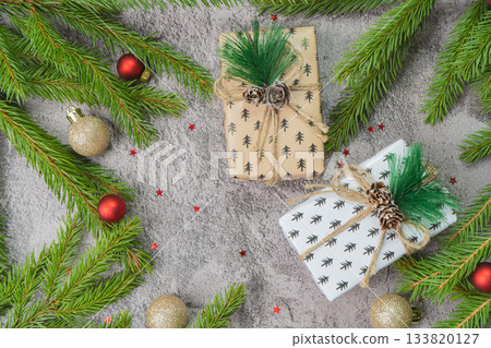 Christmas composition. Gift boxes, fir tree branches, red and gold decorations on grey background. High quality photo Christmas composition. Gift boxes, fir tree branches, red and gold decorations on grey background. High quality photo 133820127