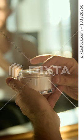 Male hands opening facial cream in soft daylight Male hands opening facial cream in soft daylight 133820250