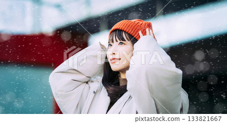 一位微笑的女子站在雪中的街角 133821667