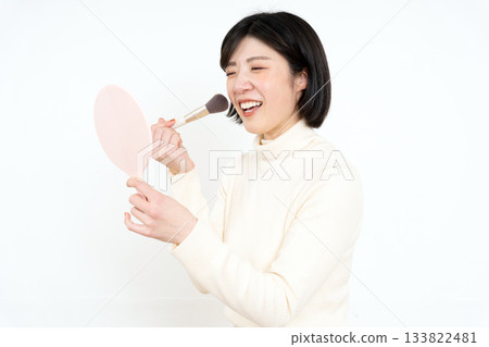 Middle-aged young woman looking at a hand mirror Middle-aged young woman looking at a hand mirror 133822481