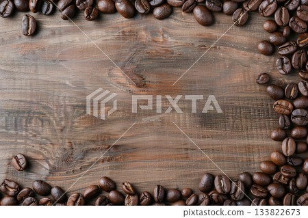 Dark roasted coffee beans are neatly placed along one edge of a warm, wooden table, creating a welcoming atmosphere for coffee lovers. The natural wood enhances the rich color of the beans 133822673