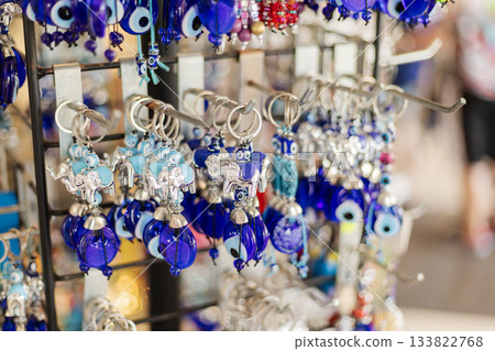 Craftsmanship shines at this market stall, featuring intricate blue keychains and charms, capturing the vibrant spirit of local artisans and shoppers enjoying the day 133822768