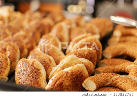A variety of freshly baked bread rolls and pastries are arranged neatly on a tray in a warm bakery setting. Customers explore the delicious options A variety of freshly baked bread rolls and pastries are arranged neatly on a tray in a warm bakery setting. Customers explore the delicious options 133822785