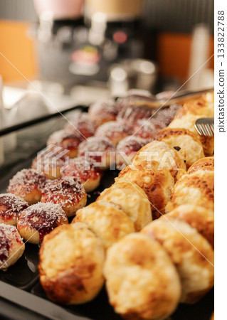 A variety of delicious pastries, including glazed donuts and flaky rolls, are arranged neatly on a bakery tray. The aroma fills the air as customers enjoy their breakfast A variety of delicious pastries, including glazed donuts and flaky rolls, are arranged neatly on a bakery tray. The aroma fills the air as customers enjoy their breakfast 133822788