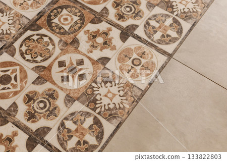 A close-up view of vintage tiles featuring various intricate designs and colors, adding character to the floor. The tiles display a mix of patterns, contributing to a cozy atmosphere 133822803