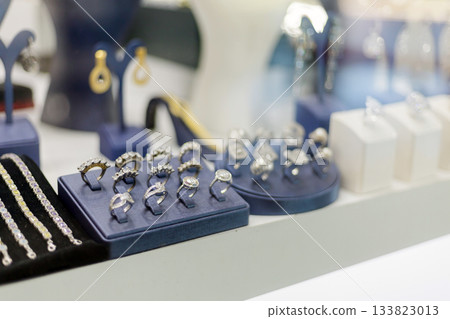 A diverse array of beautiful rings, earrings, and bracelets is displayed in an elegant jewelry store. The shiny pieces catch the light, inviting customers to admire the craftsmanship A diverse array of beautiful rings, earrings, and bracelets is displayed in an elegant jewelry store. The shiny pieces catch the light, inviting customers to admire the craftsmanship 133823013