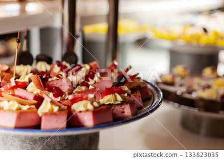A delightful assortment of desserts is presented on a table at a lively buffet. Cakes, creams, and colorful toppings create an inviting and festive atmosphere for guests enjoying the spread A delightful assortment of desserts is presented on a table at a lively buffet. Cakes, creams, and colorful toppings create an inviting and festive atmosphere for guests enjoying the spread 133823035