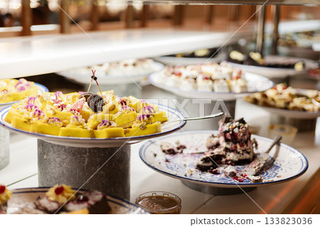 A vibrant dessert buffet features assorted sweets, including cakes and pastries, beautifully arranged on silver platters ready for guests to enjoy at a lively celebration A vibrant dessert buffet features assorted sweets, including cakes and pastries, beautifully arranged on silver platters ready for guests to enjoy at a lively celebration 133823036