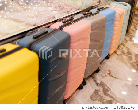 Brightly colored suitcases are neatly arranged in a store, showcasing a variety of styles and colors. Shoppers can find perfect travel solutions in this lively retail space 133823176