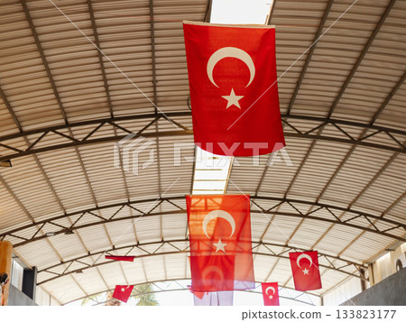 Red Turkish flags are suspended from the ceiling in a large indoor space, creating a vibrant and festive atmosphere during a cultural event in Turkey 133823177