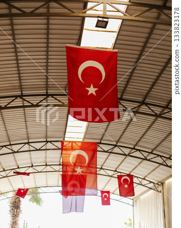 Colorful Turkish flags hang from the ceiling of a spacious hall, creating a festive atmosphere. The flags showcase the crescent moon and star emblem, symbolizing national pride 133823178