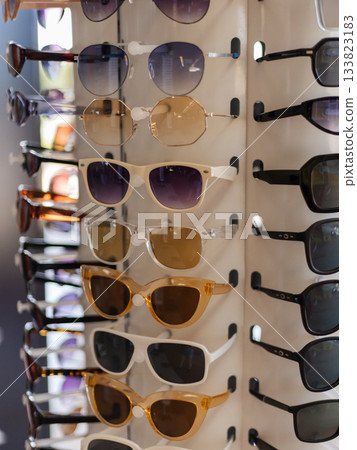 A selection of fashionable sunglasses is arranged on a display rack. The diverse styles include different shapes and shades, appealing to various tastes. Perfect for summer 133823183