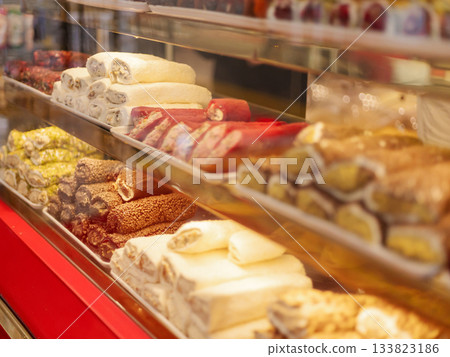 A variety of traditional sweets are neatly arranged in a local shop. The vibrant colors and diverse shapes attract customers in the warm afternoon sunlight A variety of traditional sweets are neatly arranged in a local shop. The vibrant colors and diverse shapes attract customers in the warm afternoon sunlight 133823186