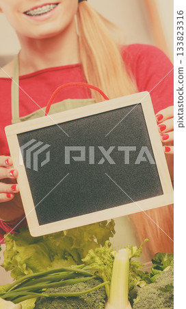 Woman having green vegetables holding board 133823316