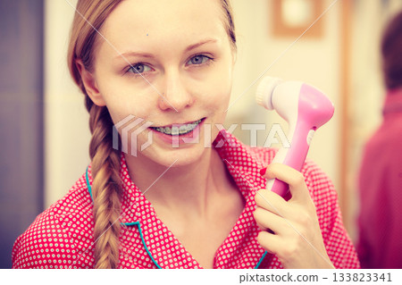 Woman using facial cleansing brush on face Woman using facial cleansing brush on face 133823341