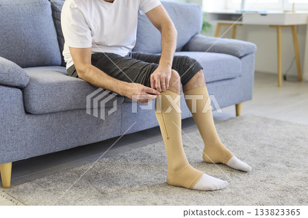 Man using compression stockings for varicose veins, zipping up elastic socks Man using compression stockings for varicose veins, zipping up elastic socks 133823365